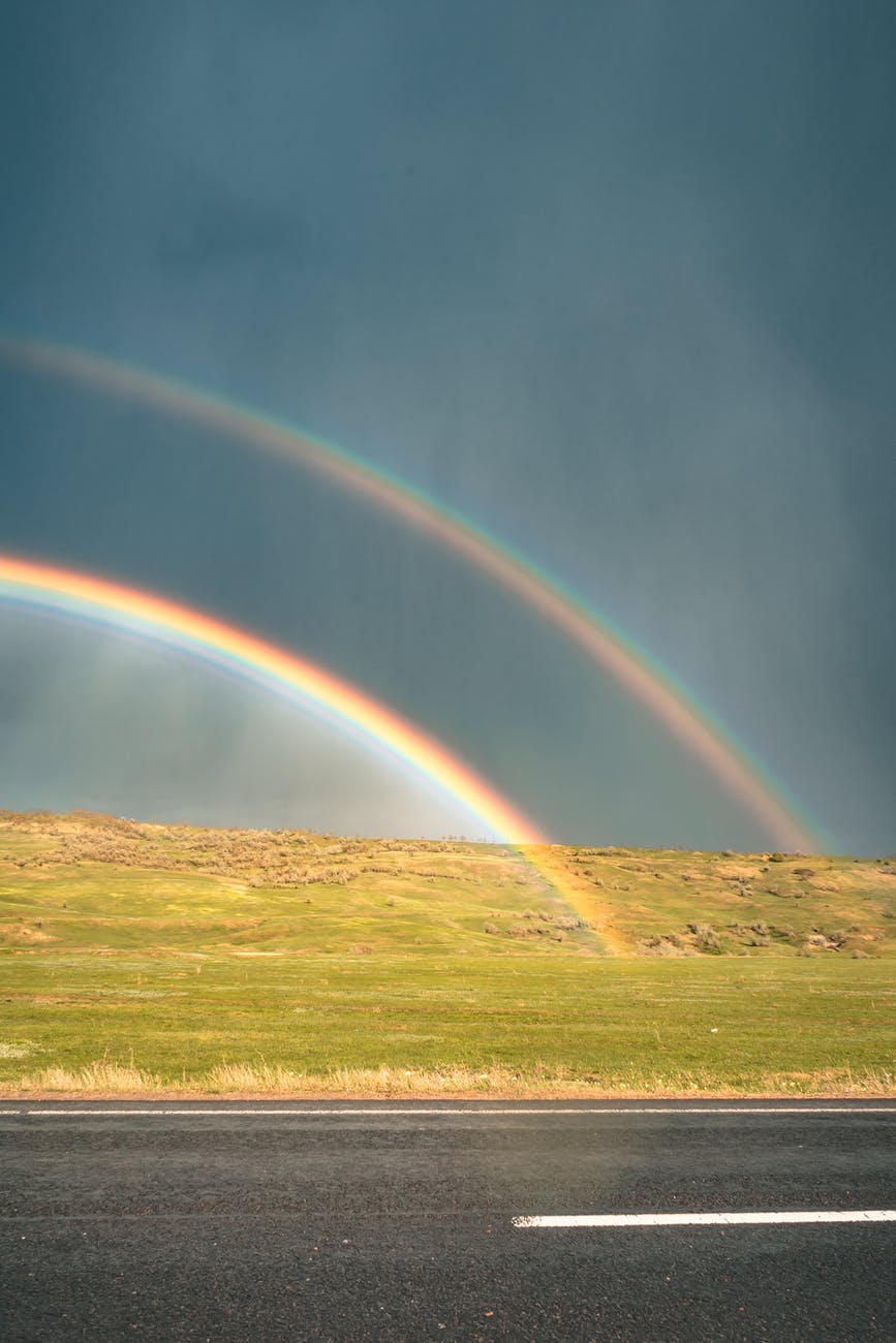 rainbow across the road during daytije