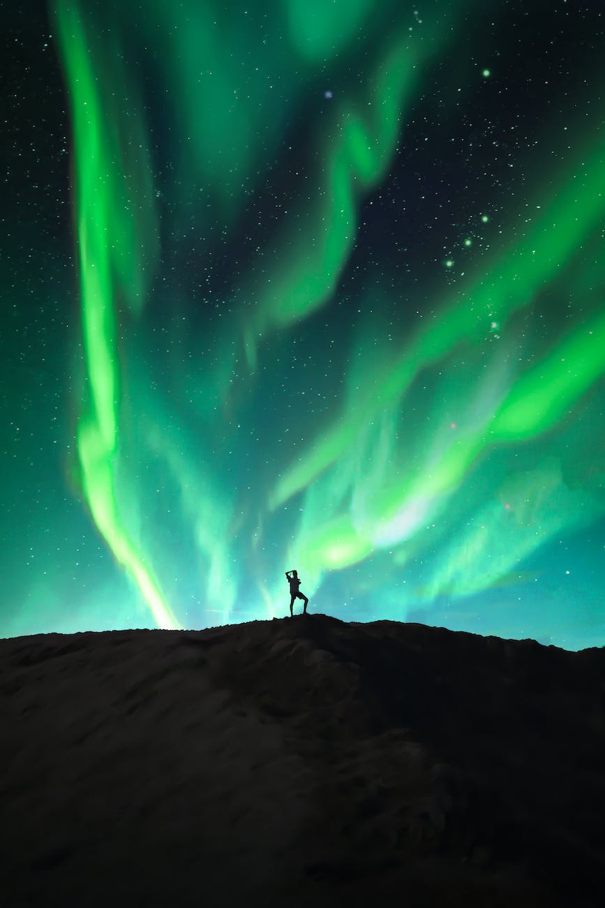 silhouette of a person under the beautiful northern lights